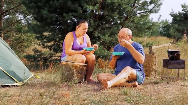 Muž a žena jedí a mluví blízko stanu. — Stock video