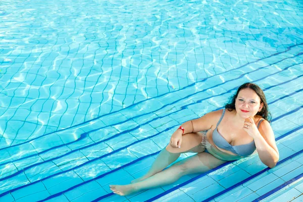 Glimlachen brunette vrouw ligt in het zwembad. — Stockfoto