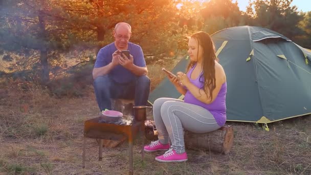 Muž a žena manželé pár v blízkosti táboráku stan hrát gadgets — Stock video