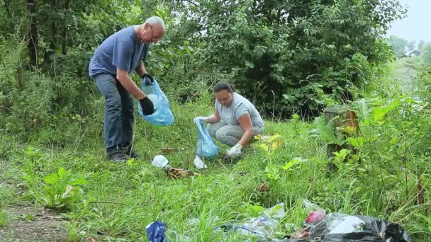Bir adam ve bir kadın parkta gönüllü olarak izinsiz çöplüklerden plastik atıkları topluyor. — Stok video