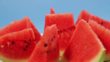 Olgun karpuz parçaları mavi arka planda bir tabakta daire şeklinde döner.