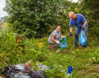 Bir erkek ve bir kadın doğadaki bir çöplüğü temizliyor. Yatay fotoğraf