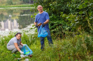 Bir kadın ve bir erkek gönüllü olarak parktaki çöpleri temizliyor..