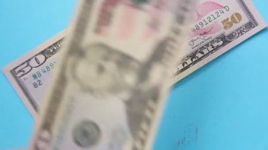 Kadın eli banknotları mavi arka plana elli ve yüz dolar koyar.