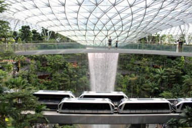 Singapur Jewel Changi Havalimanı 'ndaki Yağmur Girdabı şelalesinden geçen hava treni (Temmuz 2024' te çekildi.)