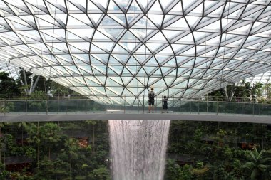 Baba oğul, Yağmur Girdabı Şelalesi 'nin yanındaki köprüde, Jewel Changi Havalimanı, Singapur' da (Temmuz 2024 'te çekildi.)