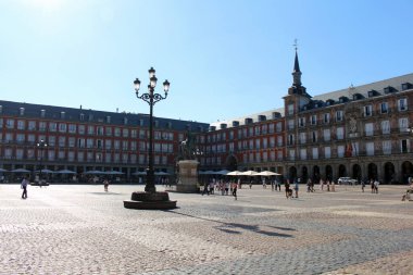 Madrid 'deki Plaza Mayor, tarihi kırmızı binaları ve parlak yaz güneşiyle. Temmuz 2024 'te çekildi.