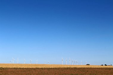 Open countryside road toward Hontanas in July 2024 line of wind turbines and wheat landscape summer sky