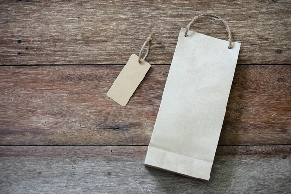 Ценник и бумажная сумка на деревянном фоне — стоковое фото