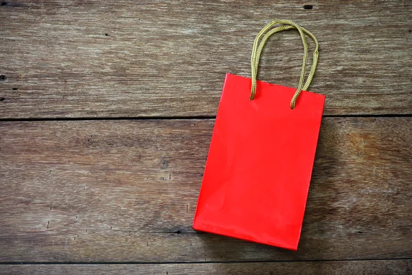 Saco de papel vermelho em um fundo de textura de madeira — Fotografia de Stock