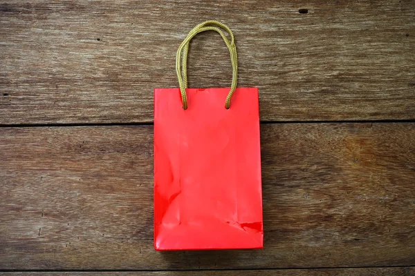 木製テクスチャ背景の赤い紙袋 — ストック写真