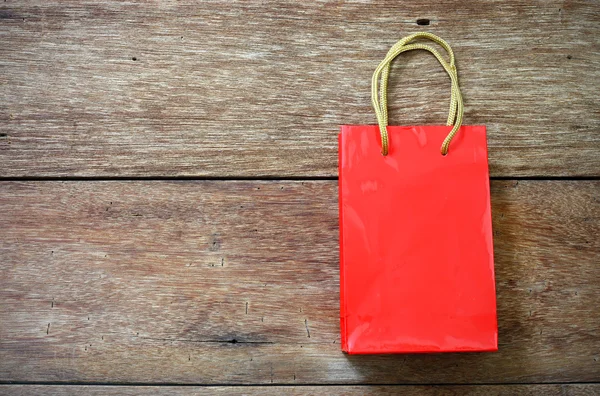 木製テクスチャ背景の赤い紙袋 — ストック写真
