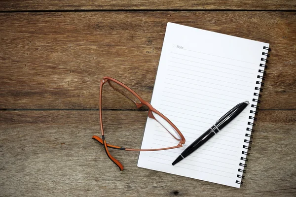 Notizbuch, Stift und Brille auf Holzgrund. — Stockfoto