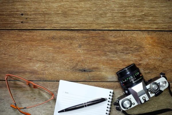 Camera, bril en Kladblok op hout — Stockfoto