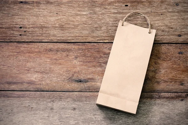 Saco de compras de papel no fundo de madeira — Fotografia de Stock