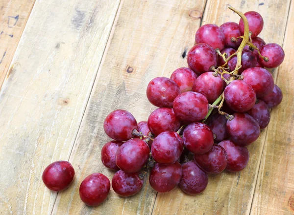 Uvas rojas sobre fondo de mesa de madera vieja — Foto de Stock