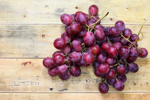 Uvas rojas sobre fondo de mesa de madera vieja — Foto de Stock