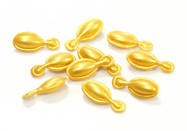 Gold cosmetic capsules on white background — Stock Photo, Image