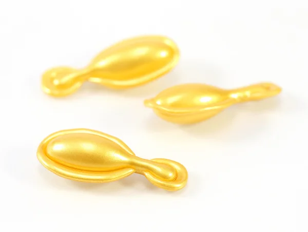 Gold cosmetic capsules on white background — Stock Photo, Image