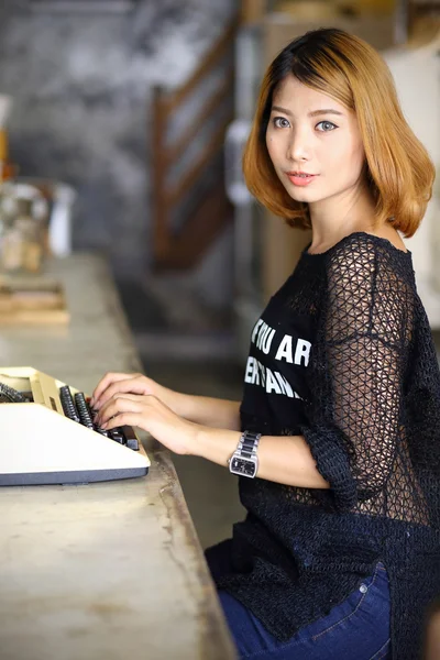 Attraente asiatico donna utilizzando macchina da scrivere in il caffè — Foto Stock