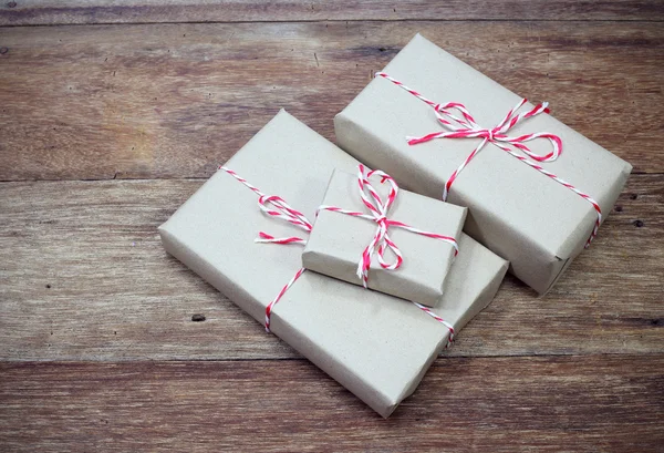 Brown paper parcel tied with red and white string on wood table — Stock Photo, Image