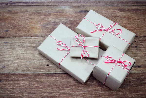 Brown paper parcel tied with red and white string on wood table — Stock Photo, Image