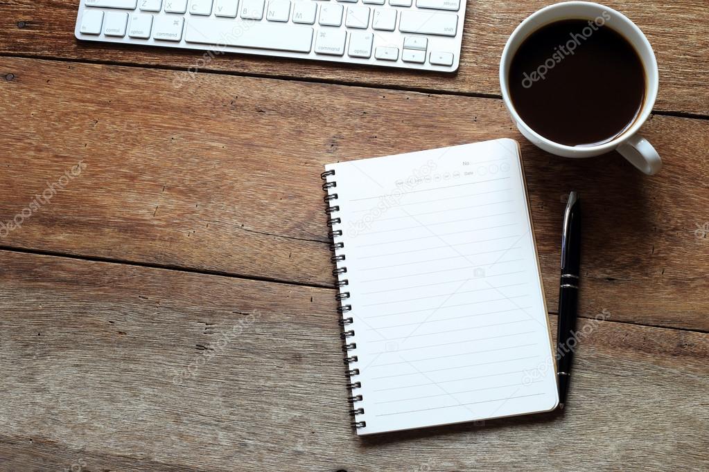 coffee, notebooks, pen and computer keyboard on desk