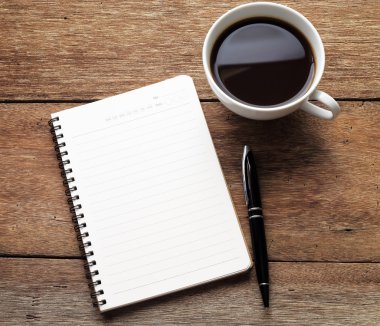 Bir boş beyaz defter, kalem ve ahşap masa kahve açmak