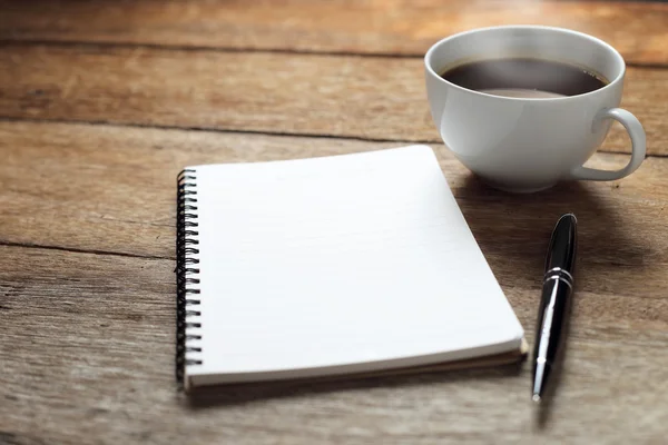 Abra um caderno branco em branco, caneta e xícara de café na mesa de madeira — Fotografia de Stock