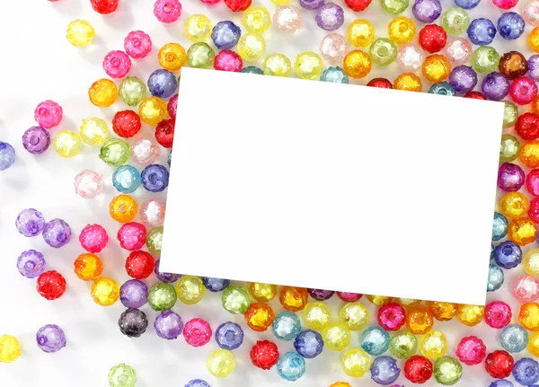 Empty white paper on colorful beads on white background — Stock Photo, Image