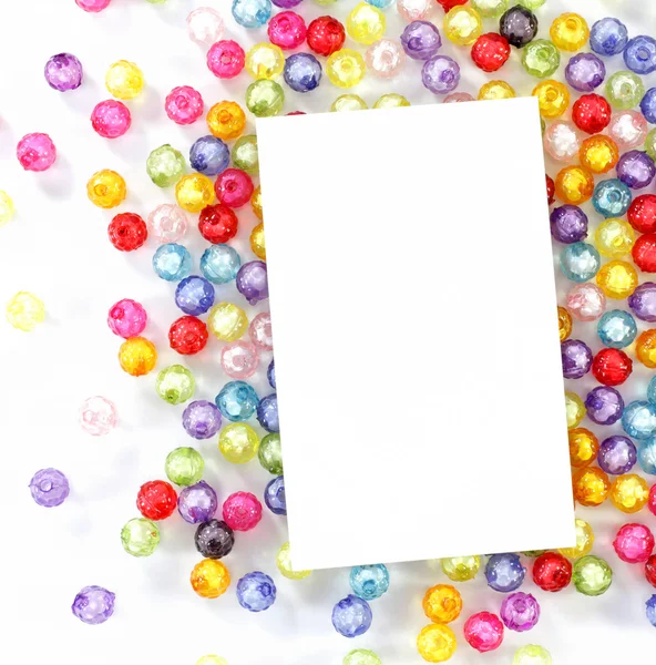 Empty white paper on colorful beads on white background — Stock Photo, Image