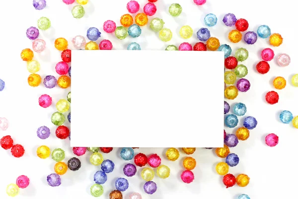 Empty white paper on colorful beads on white background — Stock Photo, Image