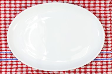 Kırmızı ekose desenli masa örtüsü üzerinde beyaz tabak