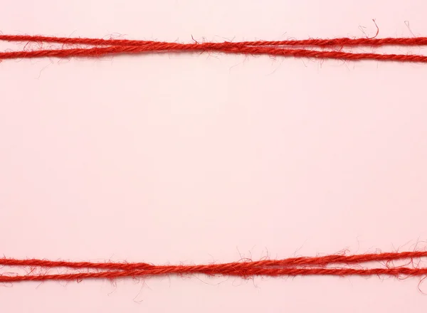 String vermelho como moldura no fundo rosa — Fotografia de Stock