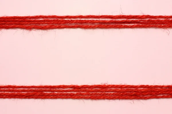 String vermelho como moldura no fundo rosa — Fotografia de Stock