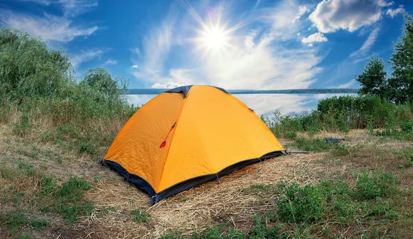 明るい太陽の下で湖によるオレンジ観光テント — ストック写真