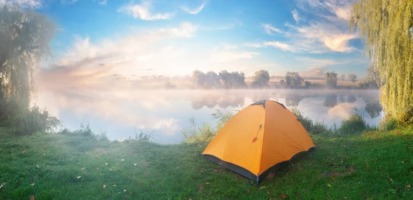 Orangefarbenes Zelt am Ufer des Flusses am frühen Morgen mit Nebel bedeckt — Stockfoto