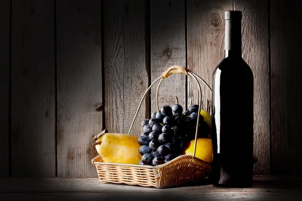 Natureza morta com um vinho de garrafa e cesta de fruto — Fotografia de Stock