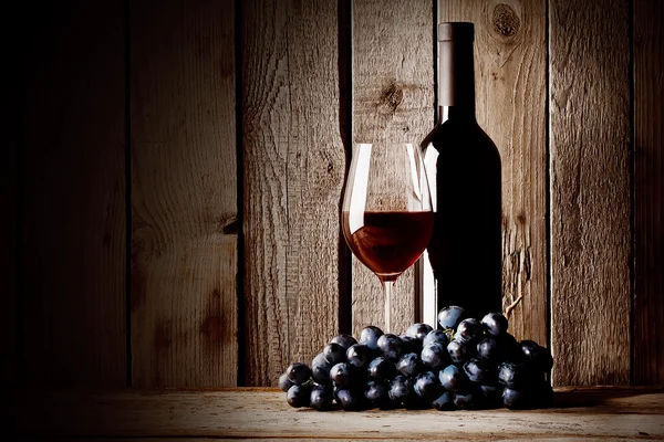 Garrafa de vinho tinto com um copo e uvas — Fotografia de Stock