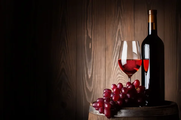Garrafa e copo de vinho tinto com uvas — Fotografia de Stock