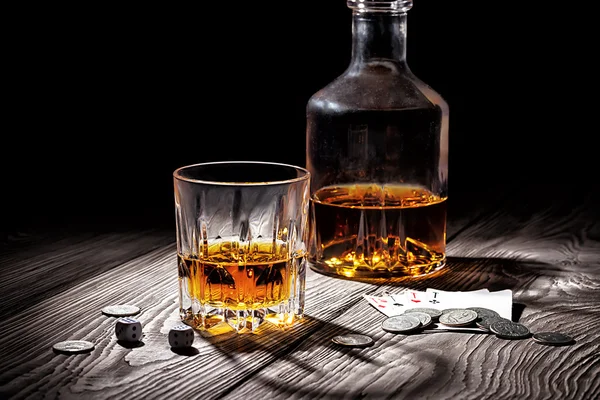 Glass and bottle of whiskey and playing cards and money — Stock Photo, Image