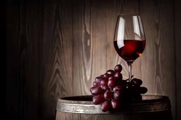 Copo de vinho tinto com uvas em barril de madeira — Fotografia de Stock