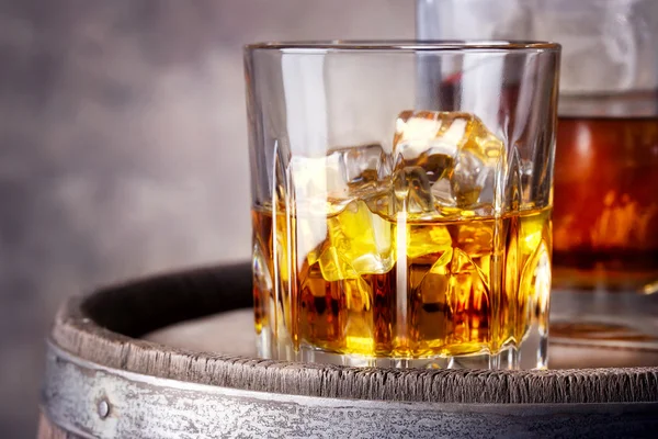 Faceted glass of whiskey with ice — Stock Photo, Image