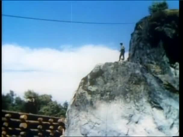 Man on zipline knocking man off rock — 图库视频影像