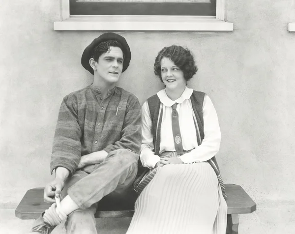 Young man and woman sitting outdoors — Stock Photo, Image