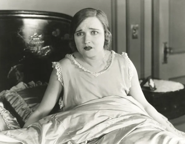 Woman sitting on bed Stock Picture