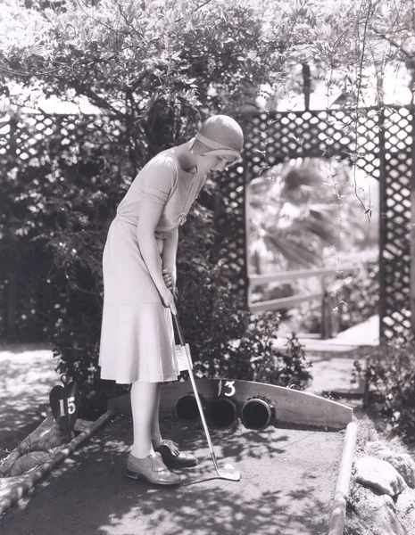 Frau spielt Minigolf Stockfoto