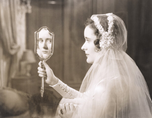 Bride gazing into hand mirror