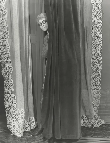 Femme écoutant derrière le rideau — Photo