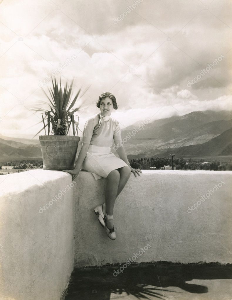 Woman sitting on outdoor ledge